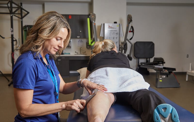 A physical therapist uses a technique called instrument-assisted soft tissue mobilization to work on a patients lower leg muscles.