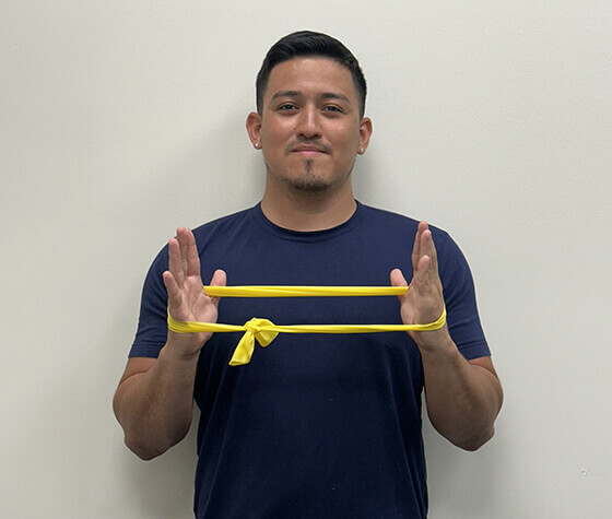 A male physical therapist with an exercise band wrapped around his hands in resting position. 